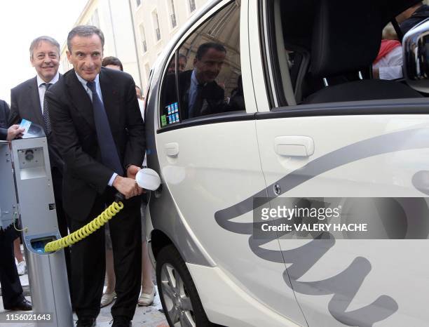 Le Président, Directeur Général d'EDF, Henri Proglio recharge une voiture électrique aux côtés du Président Directeur Général de Veolia Environnement...
