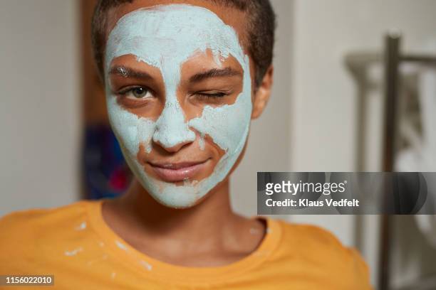 close-up of woman winking at home - gesichtsmaske kosmetik stock-fotos und bilder