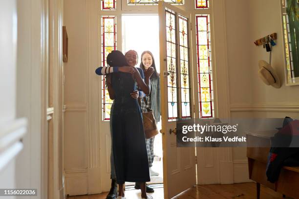 woman embracing smiling friend at doorway - welcome home photos et images de collection
