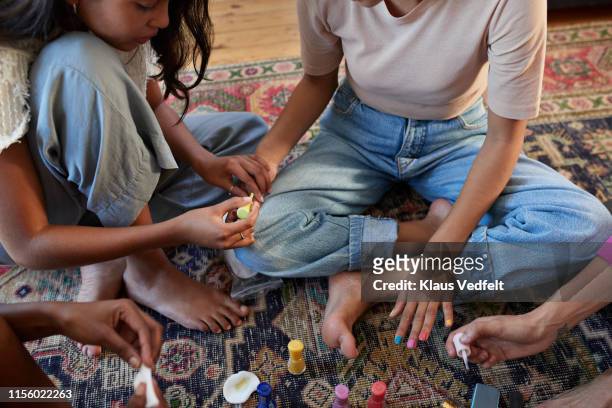 woman applying multi colored nail polish to friend - multi coloured nails stock pictures, royalty-free photos & images