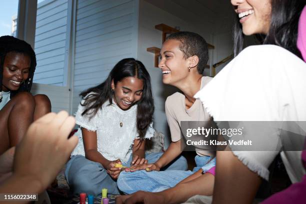 cheerful friends applying nail polish at home - doing a favor stock pictures, royalty-free photos & images