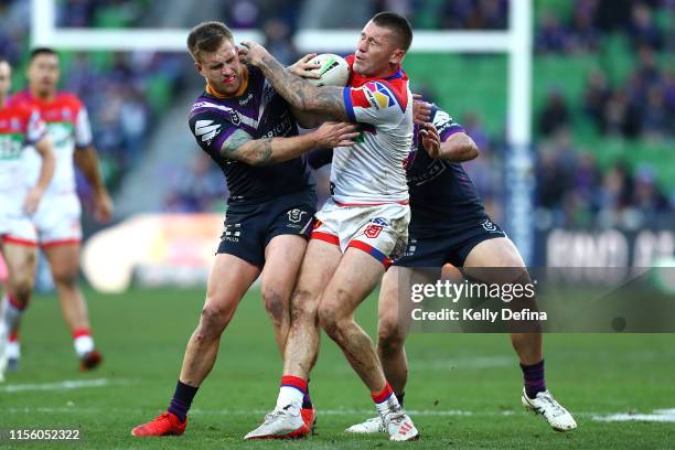 Shaun Kenny-Dowall of the Knights is tackled by Cameron Munster of the Storm during the round 14 NRL match between the Melbourne Storm and the...