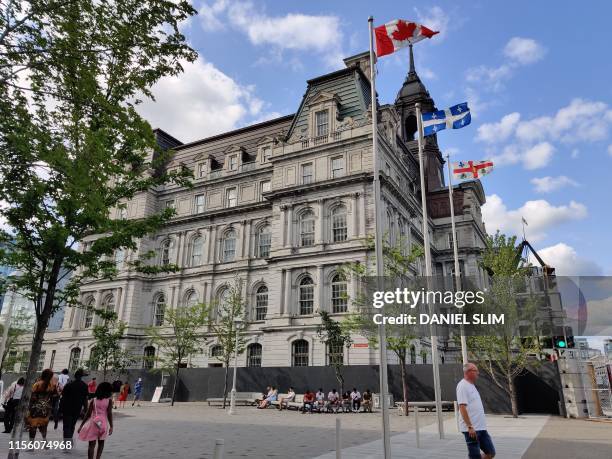 People walk by Montreal City Hall on July 14, 2019 in Montreal, Quebec. - The building was designed by architects Henri-Maurice Perrault and...