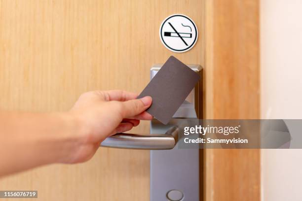 a young man is opening a door using a room key - カードキー ストックフォトと画像