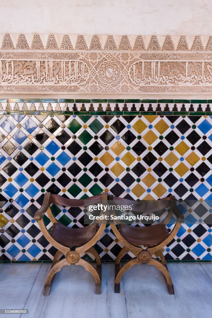 Chairs and tiles wall in the Alhambra