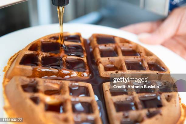 pouring syrup on waffle - stroopwafel stockfoto's en -beelden