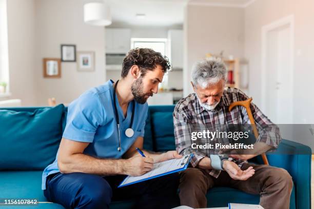 male nurse measuring blood pressure - male at home imagens e fotografias de stock