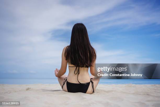 rear view of young woman meditating on beach - kota kinabalu beach stock pictures, royalty-free photos & images