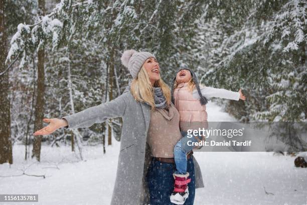mother holding daughter outside in winter. - catching snowflakes stock pictures, royalty-free photos & images