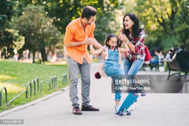 young family with daughter skateboarding in the park - mother and daughter riding on skateboard in park stock pictures, royalty-free photos & images