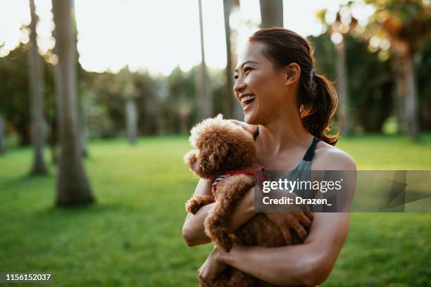 mooie taiwanese sportvrouw met hond in het park - taiwanese ethnicity stockfoto's en -beelden
