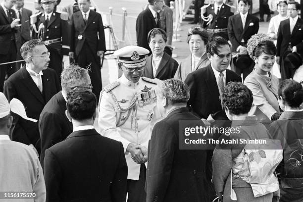 King Bhumibol and Queen Sirikit of Thailand are welcomed by Emperor Hirohito and Empress Nagako on arrival at Haneda Airport on May 27, 1963 in...