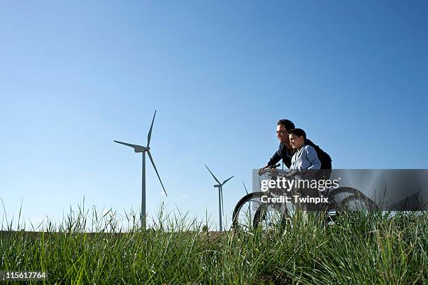 father and son with bikes by a windfarm - wind fahrrad stock-fotos und bilder