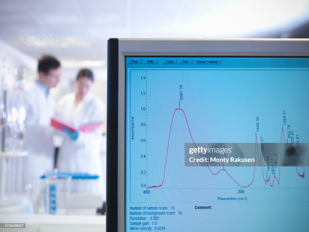 Male and female scientists discussing notes in background in laboratory