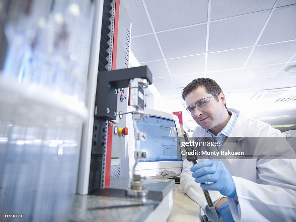 Male scientist conducting stretch test in laboratory, holding measurement tool