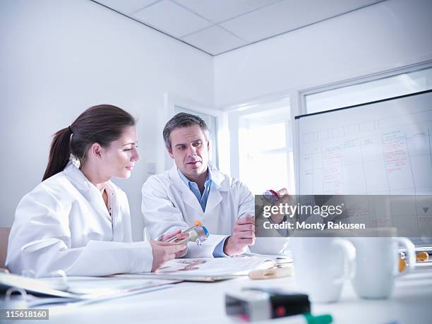 male and female scientists in office discuss product prototypes they are holding. - 製品　実験 ストックフォトと画像