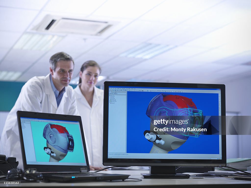 Male and female scientists look at on-screen CAD drawings of product prototypes in laboratory