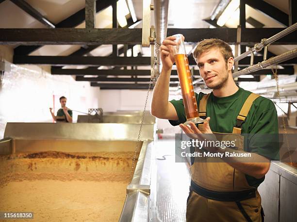 workers with sample in fermentation room - bier brouwen stockfoto's en -beelden