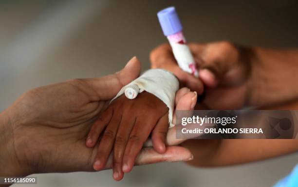 Nurse holds a test tube after extracting blood from a child presumed to be infected with dengue, which vector is the Aedes aegypti, at the Roberto...