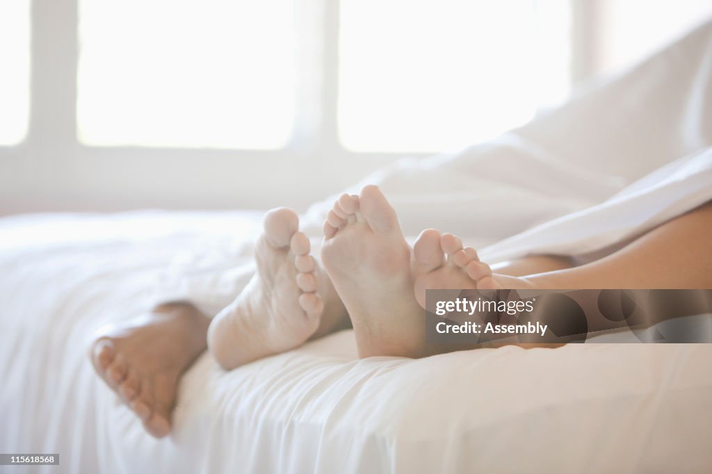 Close up of couple's feet in bed