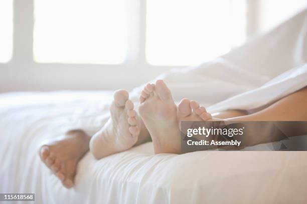 close up of couple's feet in bed - couple cuddling in bed stock pictures, royalty-free photos & images