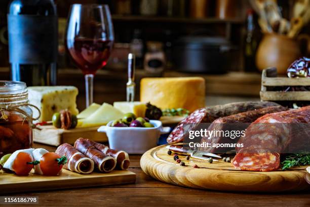 tapas of cheese, cured ham, salami wine and chorizo on a rustic wooden table - spanish culture stock pictures, royalty-free photos & images