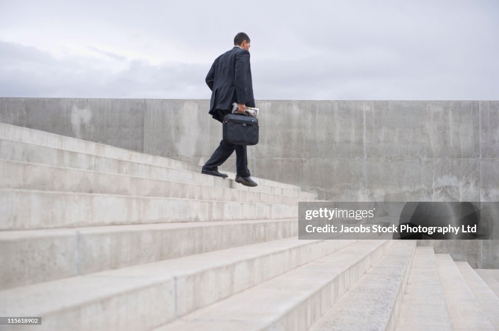 Hispanic businessman with briefcase walking down stairs