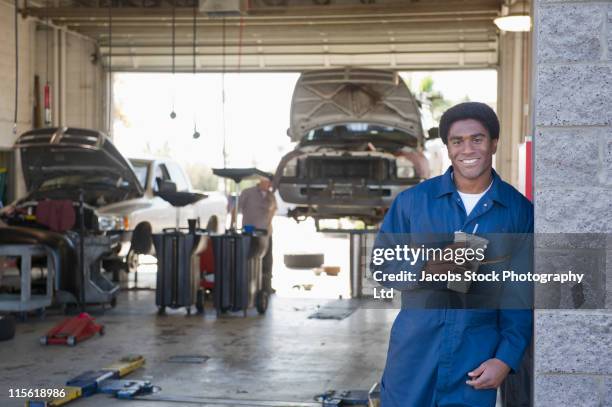 mixed race mechanic taking break in auto repair shop - drinking soda in car stock pictures, royalty-free photos & images