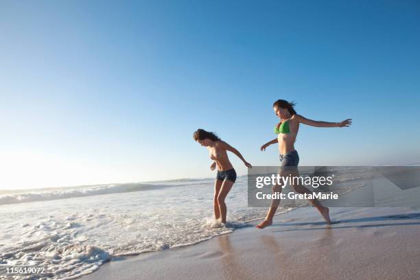 duas meninas na praia em execução - com os pés na água imagens e fotografias de stock