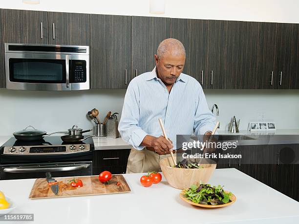 black man preparing salad in kitchen - salad tossing stock pictures, royalty-free photos & images