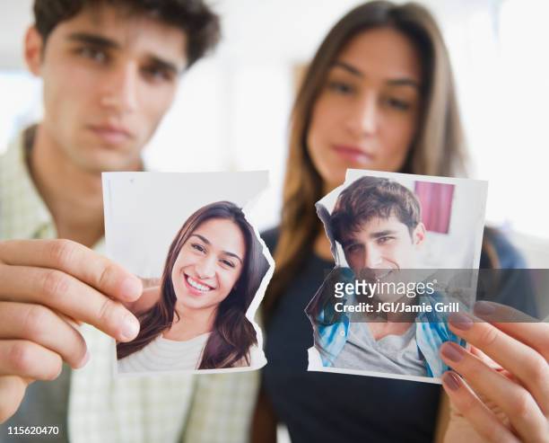 couple holding torn photograph - relación humana fotografías e imágenes de stock