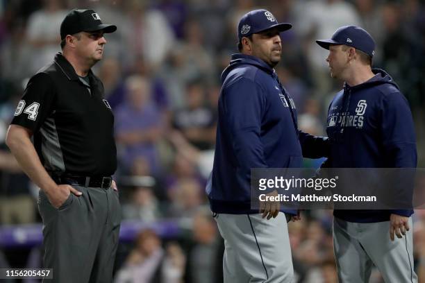 Manager Andy Green of the San Diego Padres is restrained from first base umpire Lance Barrett by Rod Barajas after being ejected in the sixth inning...