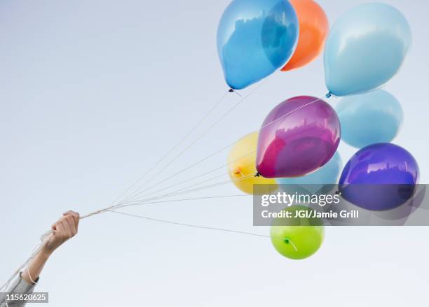 caucasian woman holding bunch of balloons - hands in the air stock-fotos und bilder