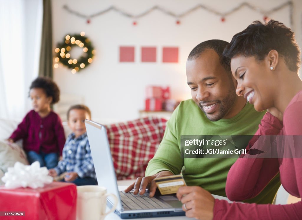 Black mother and father shopping online with credit card