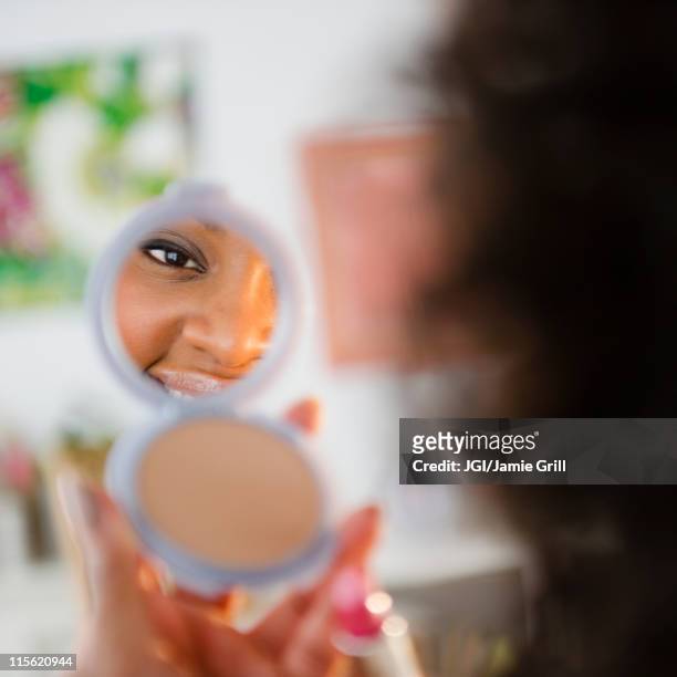 african american woman looking at reflection in compact - woman lipstick rearview stock pictures, royalty-free photos & images