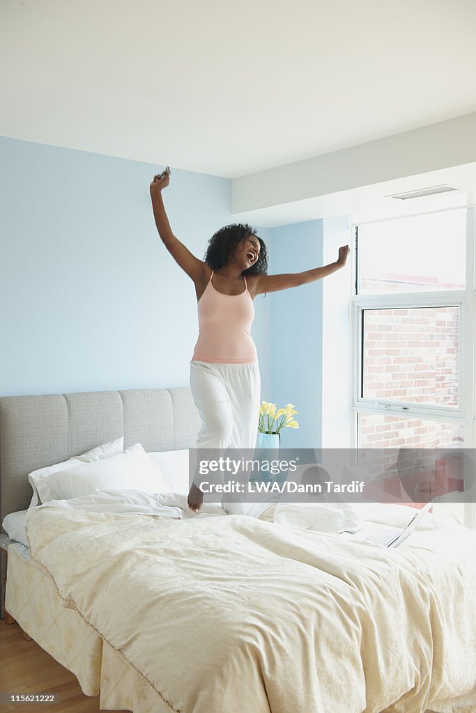 Black woman jumping on bed