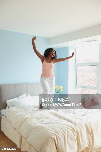 black woman jumping on bed - black woman jumping on bed stock pictures, royalty-free photos & images