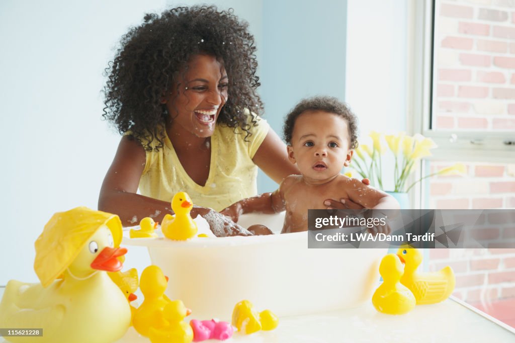 Mother washing baby in tub with rubber ducks