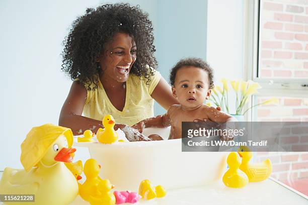 mother washing baby in tub with rubber ducks - bañando bebe fotografías e imágenes de stock