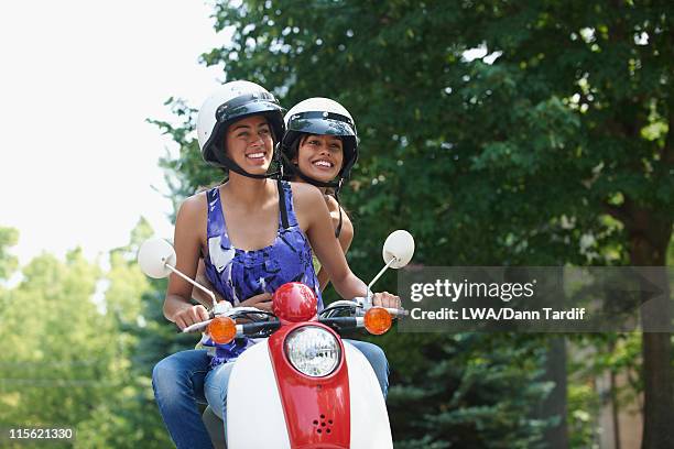 hispanic friends riding scooter together - girl riding scooter stockfoto's en -beelden