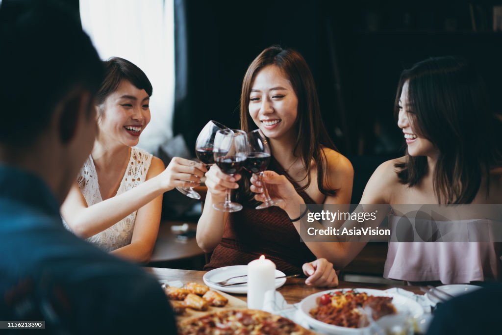 Group of joyful young Asian woman having fun and toasting with red wine during party