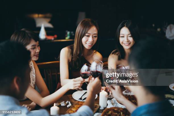 groep van vrolijke jonge aziatische man en vrouw met plezier en toasting met rode wijn tijdens de partij - asian couple dinner stockfoto's en -beelden