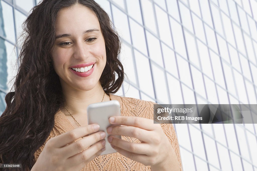Mixed race woman text messaging on cell phone