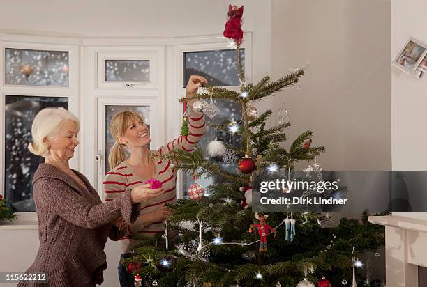 a mother and daughter decorating a tree - kerstboom versieren stockfoto's en -beelden