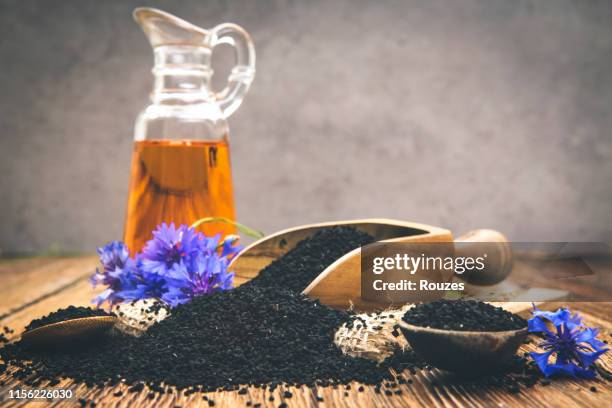 black cumin seeds essential oil with wooden spoon and shovel on wooden background - seeded stock pictures, royalty-free photos & images