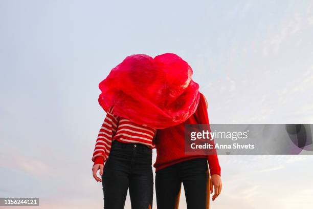 Two figures wearing a red and red plastic bag on the head against the sky