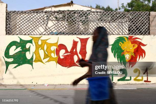 Pedestrian walks past a graffiti reading Senegal with coulours of the flag of Senegal in Dakar on July 18 on the eve of the final of the Africa Cup...