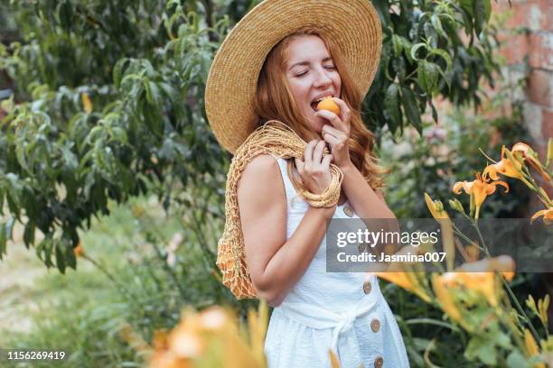 young  woman eating apricot  in garden - eating human flesh stock pictures, royalty-free photos & images