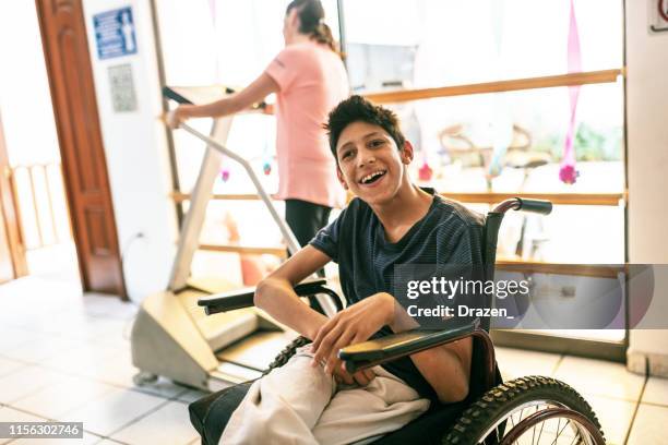 smiling latino boy with celebral palsy in day care nursery. - learning disabilities stock pictures, royalty-free photos & images