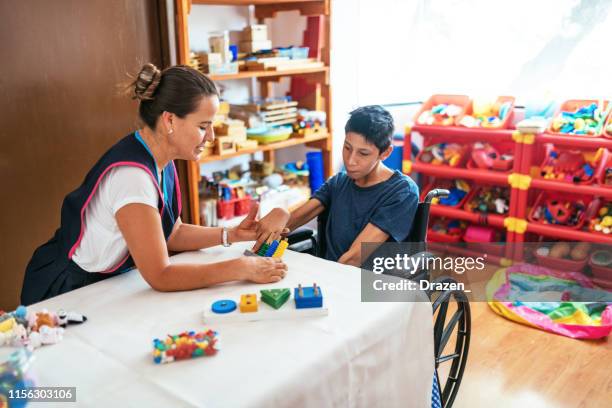 living with terminal disability - latino boy with celebral palsy in day care - learning disability nurse stock pictures, royalty-free photos & images